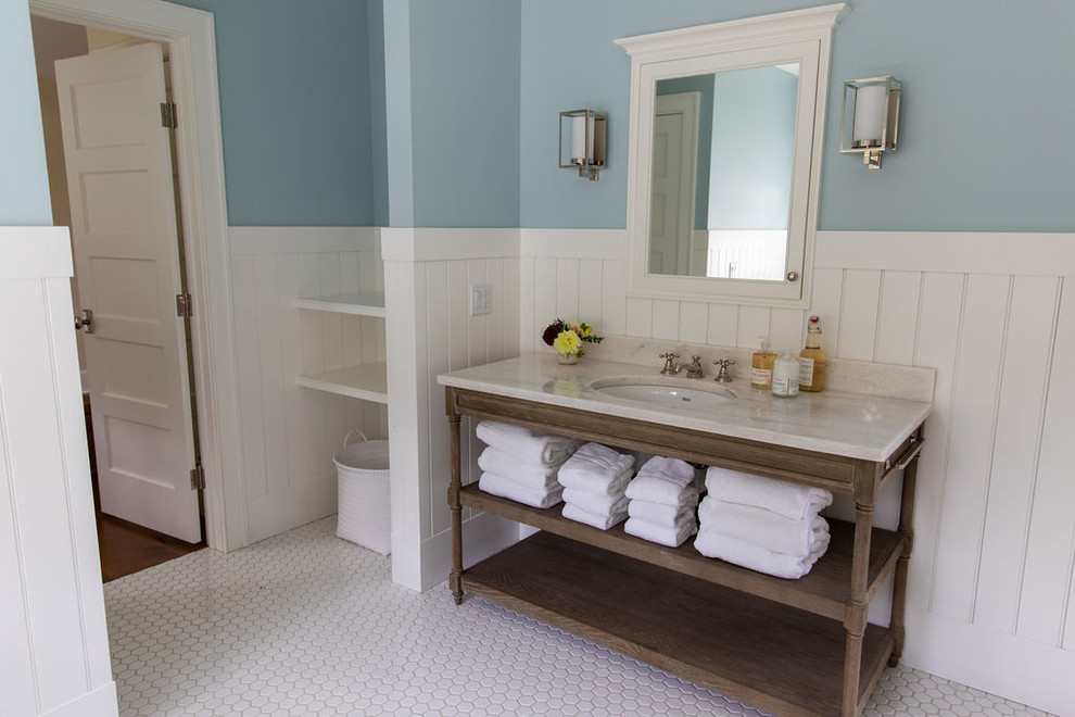 Immagine di una grande stanza da bagno country con consolle stile comò, ante in legno chiaro, vasca da incasso, pareti blu, pavimento con piastrelle a mosaico, lavabo sottopiano, top in marmo, pavimento bianco e top bianco