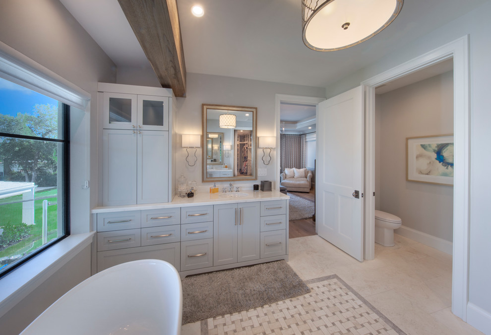 Large traditional ensuite bathroom in Miami with shaker cabinets, blue cabinets, a freestanding bath, a walk-in shower, blue walls, medium hardwood flooring, a built-in sink, brown floors, an open shower and grey worktops.