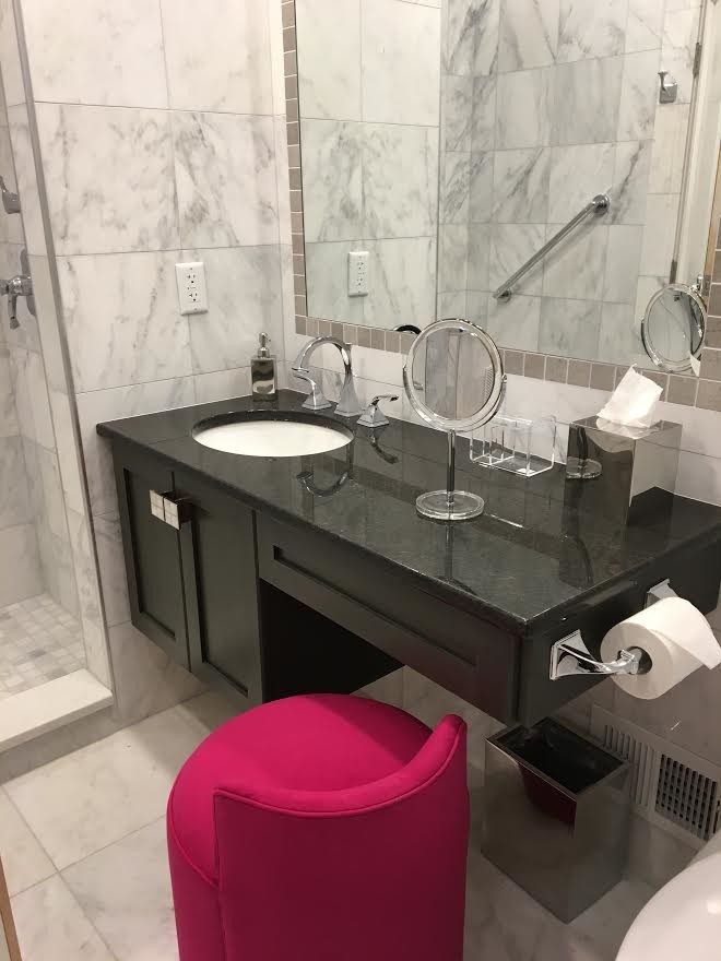 Mid-sized transitional 3/4 gray tile and marble tile marble floor and gray floor alcove shower photo in New York with shaker cabinets, black cabinets, gray walls, an undermount sink, quartz countertops, a hinged shower door and black countertops