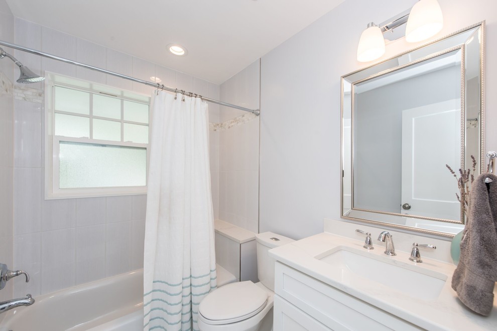 Exempel på ett mellanstort klassiskt vit vitt badrum med dusch, med skåp i shakerstil, vita skåp, ett badkar i en alkov, en dusch/badkar-kombination, en toalettstol med separat cisternkåpa, vit kakel, keramikplattor, grå väggar, ett undermonterad handfat, bänkskiva i akrylsten och dusch med duschdraperi