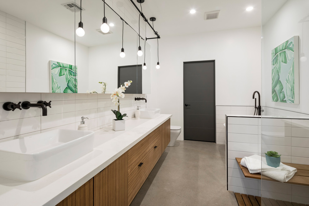 Photo of a medium sized contemporary ensuite bathroom in Phoenix with flat-panel cabinets, medium wood cabinets, a freestanding bath, a corner shower, white tiles, ceramic tiles, white walls, concrete flooring, a vessel sink, solid surface worktops, grey floors and white worktops.