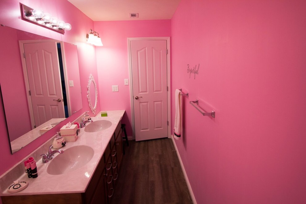 インディアナポリスにある中くらいなトラディショナルスタイルのおしゃれな子供用バスルーム (落し込みパネル扉のキャビネット、濃色木目調キャビネット、ピンクの壁、濃色無垢フローリング、一体型シンク) の写真