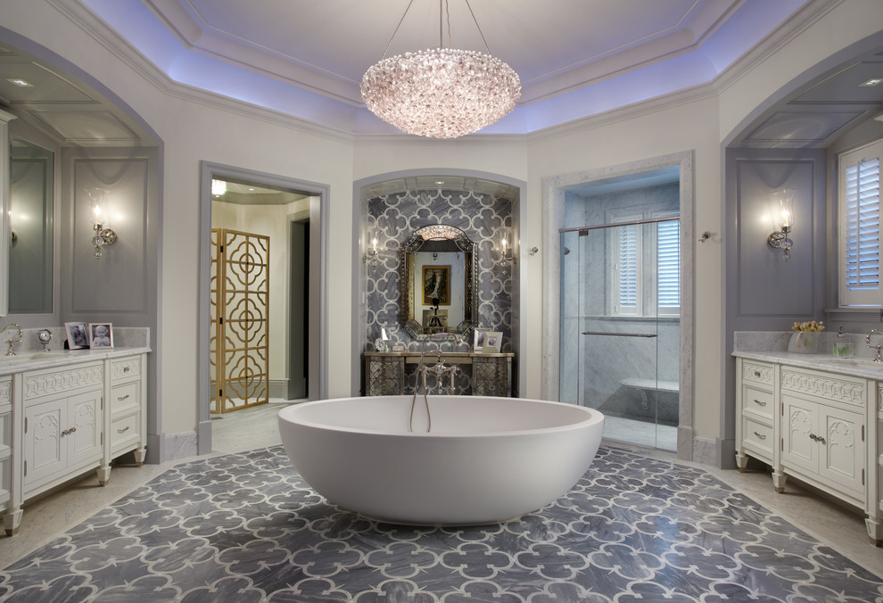 Свежая идея для дизайна: огромная главная ванная комната в классическом стиле с белыми фасадами, отдельно стоящей ванной, серой плиткой, белыми стенами, мраморным полом, врезной раковиной и фасадами с утопленной филенкой - отличное фото интерьера