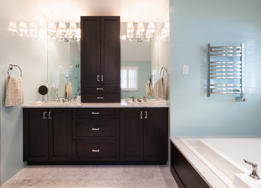 Example of a large trendy master marble floor and white floor drop-in bathtub design in New York with recessed-panel cabinets, dark wood cabinets, an undermount sink, marble countertops and white countertops