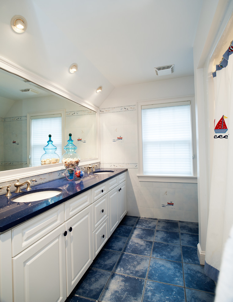 ボストンにある中くらいなビーチスタイルのおしゃれな子供用バスルーム (壁付け型シンク、レイズドパネル扉のキャビネット、白いキャビネット、クオーツストーンの洗面台、白いタイル、アルコーブ型浴槽、シャワー付き浴槽	、セラミックタイルの床、青い洗面カウンター) の写真