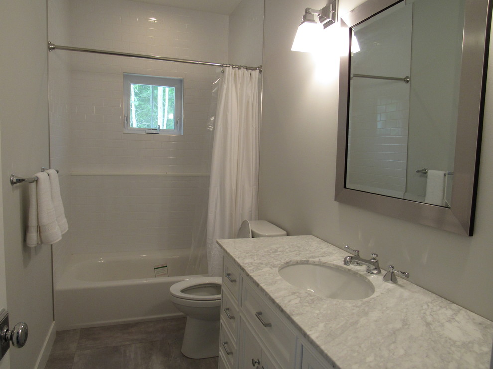 Inspiration pour une salle d'eau traditionnelle de taille moyenne avec un placard à porte affleurante, des portes de placard blanches, une baignoire en alcôve, un combiné douche/baignoire, un carrelage blanc, un carrelage métro, un mur gris, un sol en carrelage de porcelaine, un lavabo encastré, un plan de toilette en marbre, un sol gris et une cabine de douche avec un rideau.