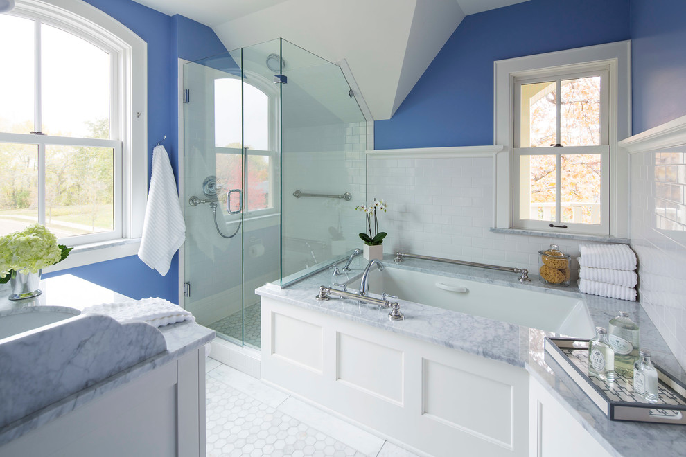 Classic bathroom in Minneapolis with a submerged sink, white cabinets, a submerged bath, a corner shower, white tiles, blue walls, flat-panel cabinets, marble worktops and marble flooring.