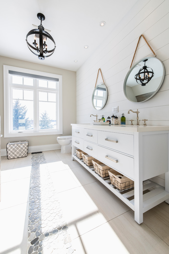 This is an example of a medium sized classic family bathroom in Toronto with freestanding cabinets, distressed cabinets, a built-in bath, an alcove shower, a two-piece toilet, beige tiles, ceramic tiles, beige walls, pebble tile flooring, a built-in sink, beige floors and a hinged door.