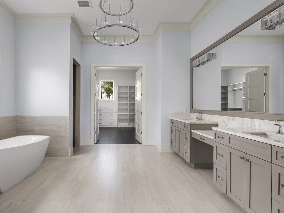 Immagine di una grande stanza da bagno padronale chic con ante in stile shaker, ante beige, vasca freestanding, pareti blu, lavabo sottopiano, top in marmo e pavimento beige