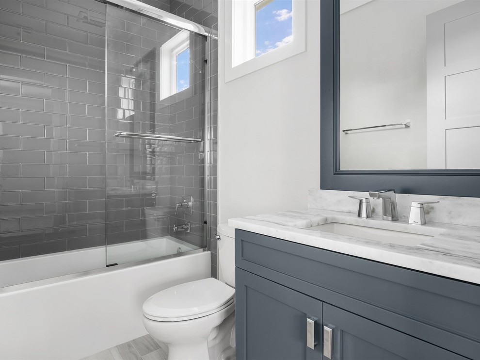 Inredning av ett klassiskt stort en-suite badrum, med skåp i shakerstil, grå skåp, ett badkar i en alkov, en dusch/badkar-kombination, en toalettstol med separat cisternkåpa, grå kakel, tunnelbanekakel, vita väggar, ett undermonterad handfat, marmorbänkskiva, grått golv och dusch med skjutdörr