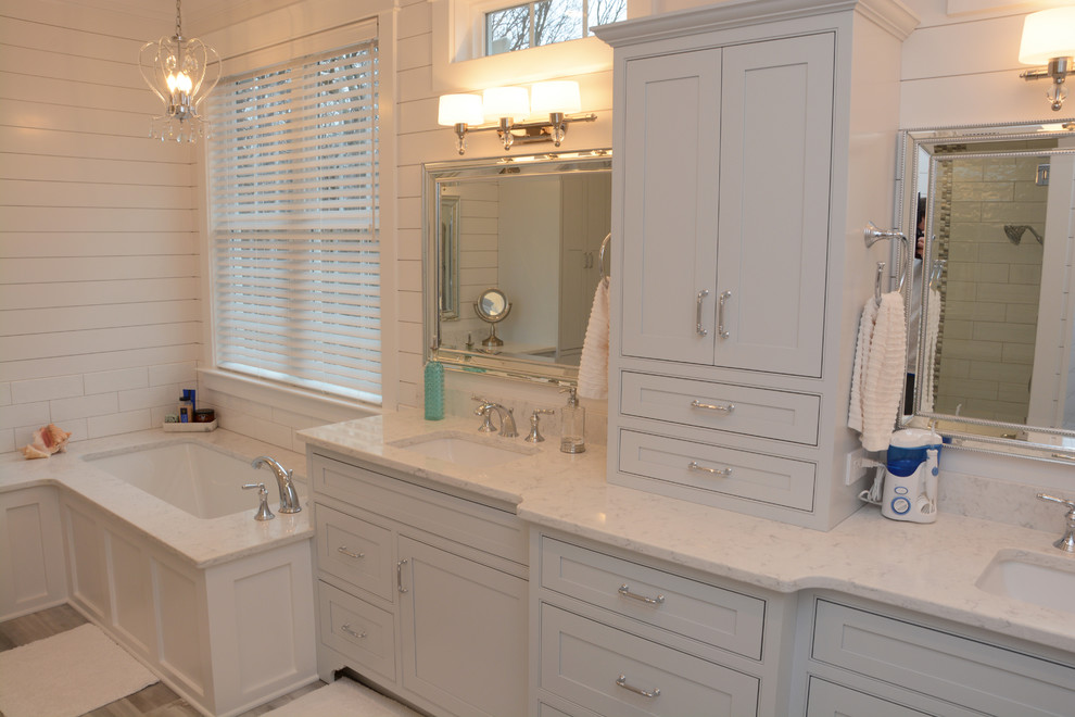 Large traditional ensuite bathroom in Baltimore with recessed-panel cabinets, blue cabinets, a corner bath, a two-piece toilet, white tiles, white walls, a submerged sink, engineered stone worktops, a hinged door and white worktops.