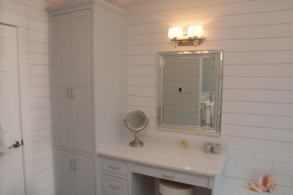 На фото: большая главная ванная комната в стиле неоклассика (современная классика) с фасадами с утопленной филенкой, синими фасадами, угловой ванной, раздельным унитазом, белой плиткой, белыми стенами, врезной раковиной, столешницей из искусственного кварца, душем с распашными дверями и белой столешницей с