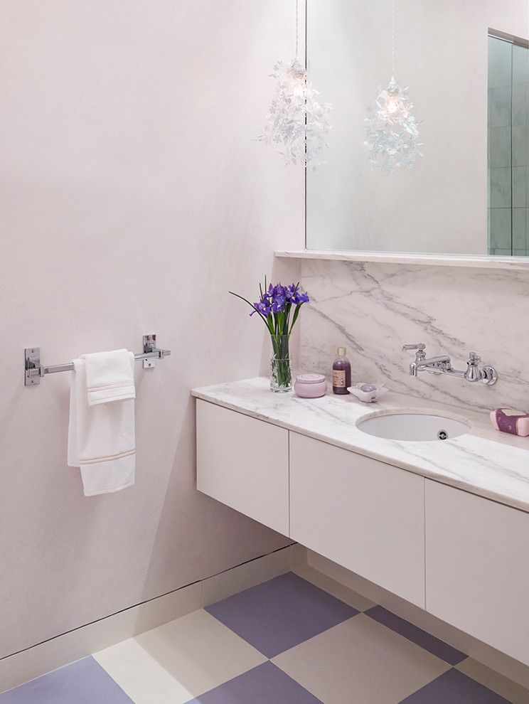 Inredning av ett modernt litet badrum för barn, med ett undermonterad handfat, släta luckor, vita skåp, marmorbänkskiva, ett platsbyggt badkar, en kantlös dusch, en toalettstol med separat cisternkåpa, vit kakel, stenhäll, lila väggar och mosaikgolv