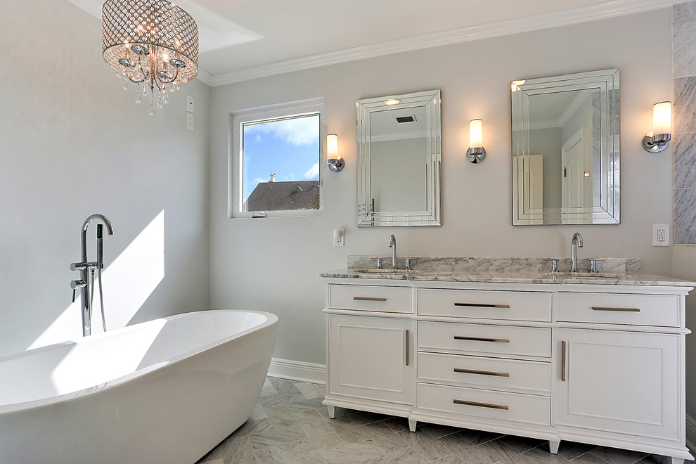 Réalisation d'une salle de bain principale design de taille moyenne avec un placard à porte affleurante, des portes de placard blanches, une baignoire indépendante, un mur gris, un sol en marbre, un lavabo encastré, un plan de toilette en marbre, un sol gris et un plan de toilette gris.