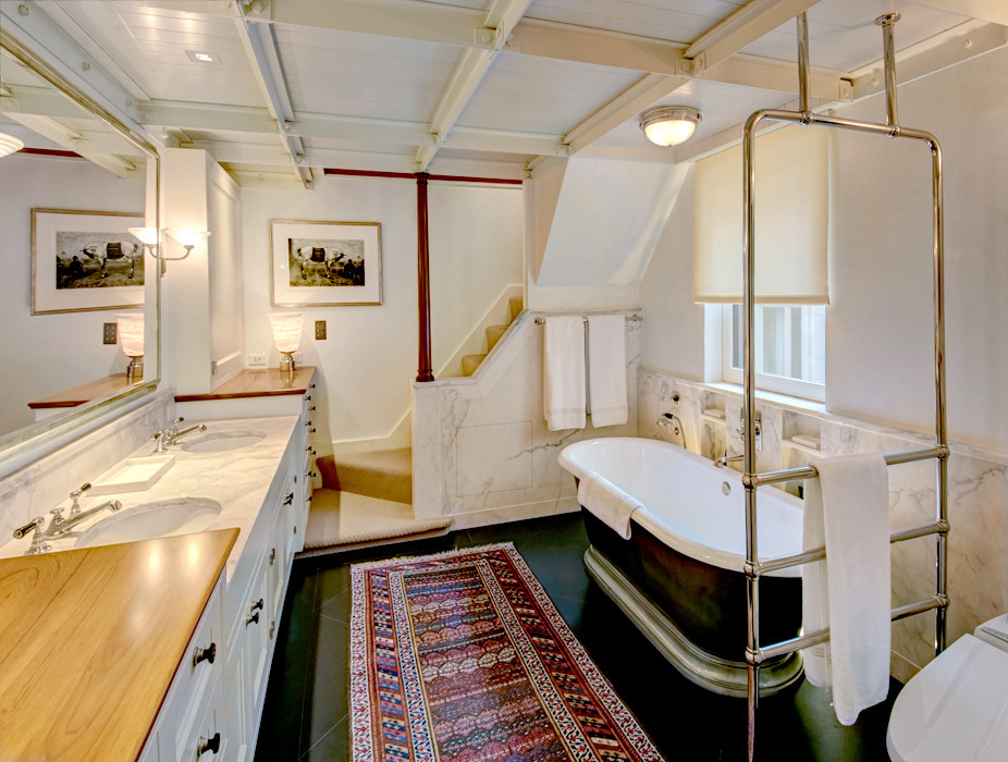 Inredning av ett klassiskt stort en-suite badrum, med ett integrerad handfat, luckor med infälld panel, vita skåp, marmorbänkskiva, ett fristående badkar, en toalettstol med hel cisternkåpa, vit kakel, stenhäll, vita väggar och marmorgolv
