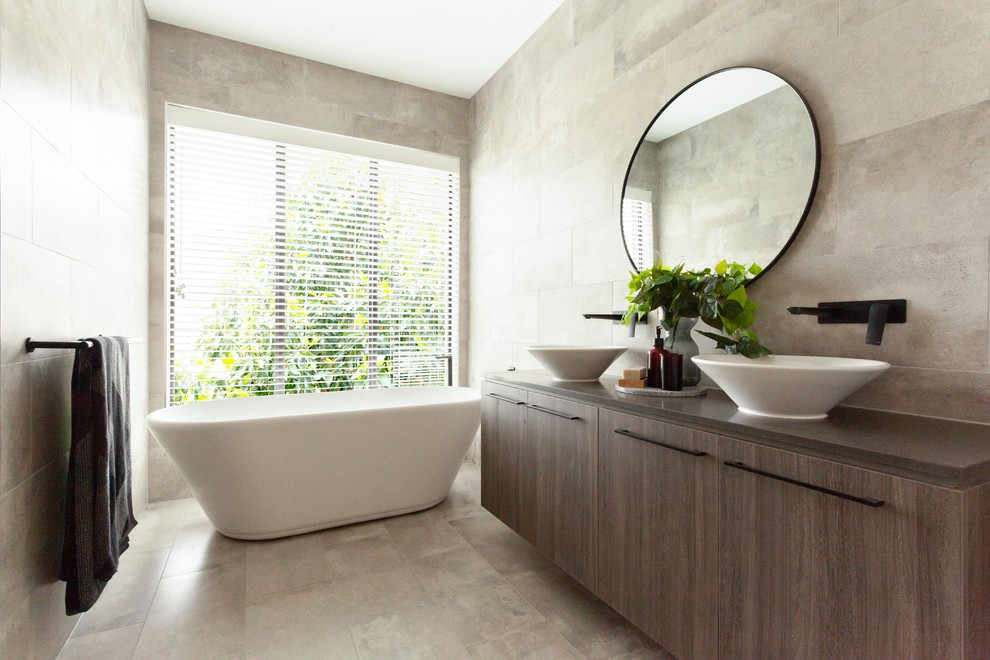 Стильный дизайн: ванная комната в современном стиле с плоскими фасадами, серыми фасадами, отдельно стоящей ванной, серой плиткой, настольной раковиной, серым полом и серой столешницей - последний тренд