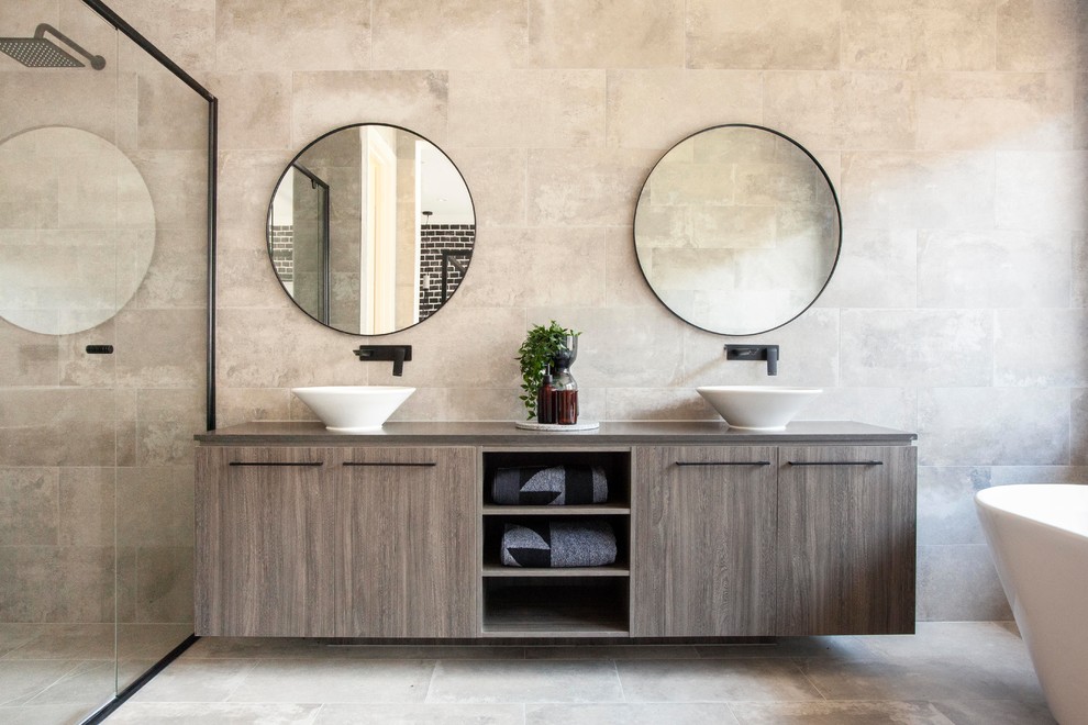 Exemple d'une douche en alcôve tendance avec un placard à porte plane, des portes de placard grises, une baignoire indépendante, un carrelage gris, un mur gris, un lavabo encastré, un sol gris et un plan de toilette gris.