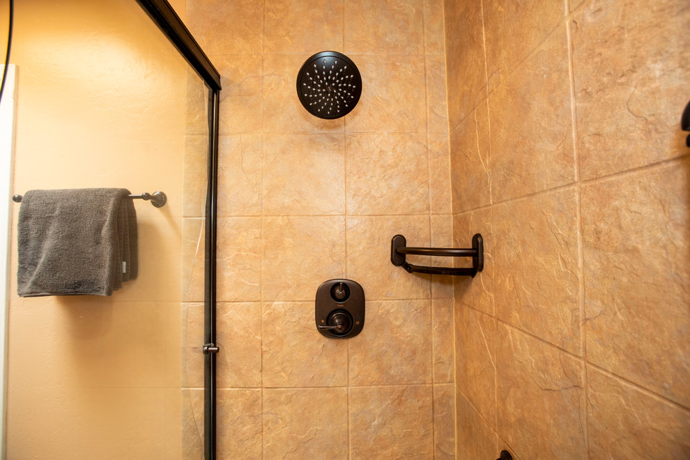 Foto på ett litet amerikanskt en-suite badrum, med luckor med infälld panel, skåp i ljust trä, en dusch i en alkov, en toalettstol med hel cisternkåpa, beige kakel, klinkergolv i keramik, ett integrerad handfat, flerfärgat golv och dusch med skjutdörr