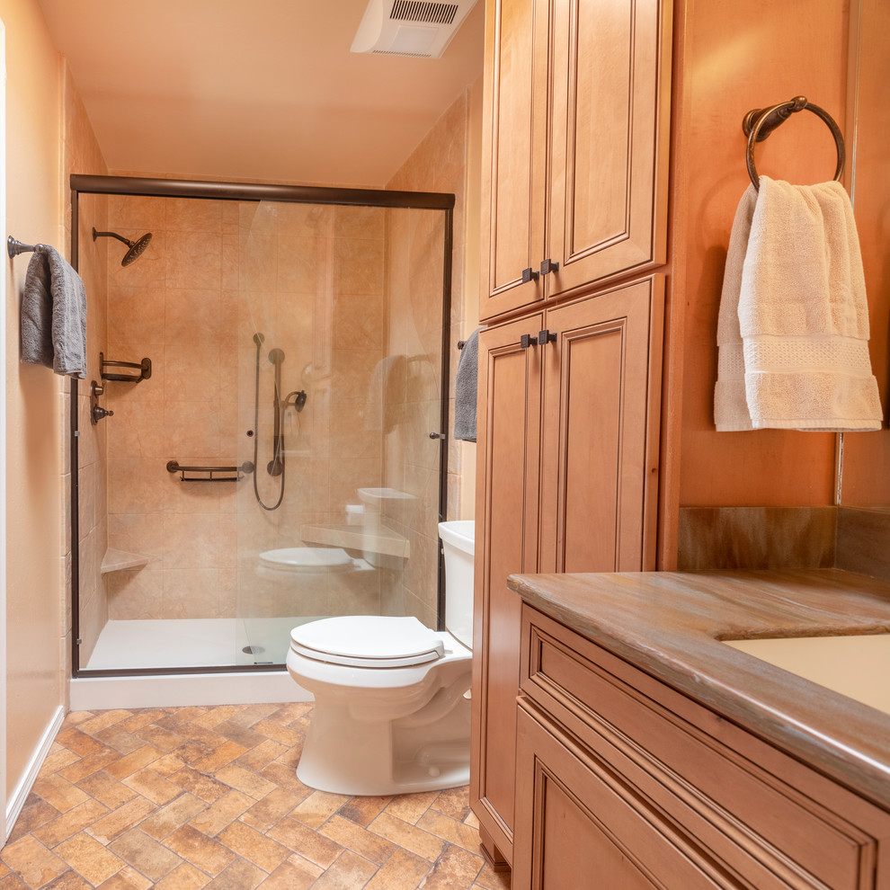 Kleines Mediterranes Badezimmer En Suite mit Schrankfronten mit vertiefter Füllung, hellen Holzschränken, Duschnische, Toilette mit Aufsatzspülkasten, beigen Fliesen, Keramikboden, integriertem Waschbecken, buntem Boden und Schiebetür-Duschabtrennung in Albuquerque