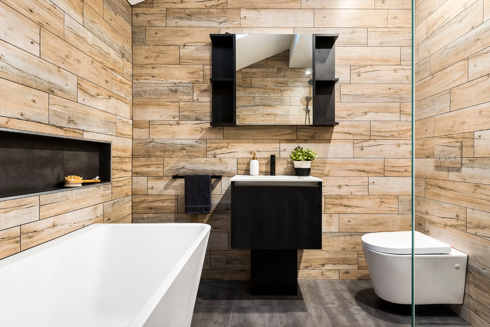 Foto på ett funkis badrum, med släta luckor, svarta skåp, en vägghängd toalettstol och brun kakel