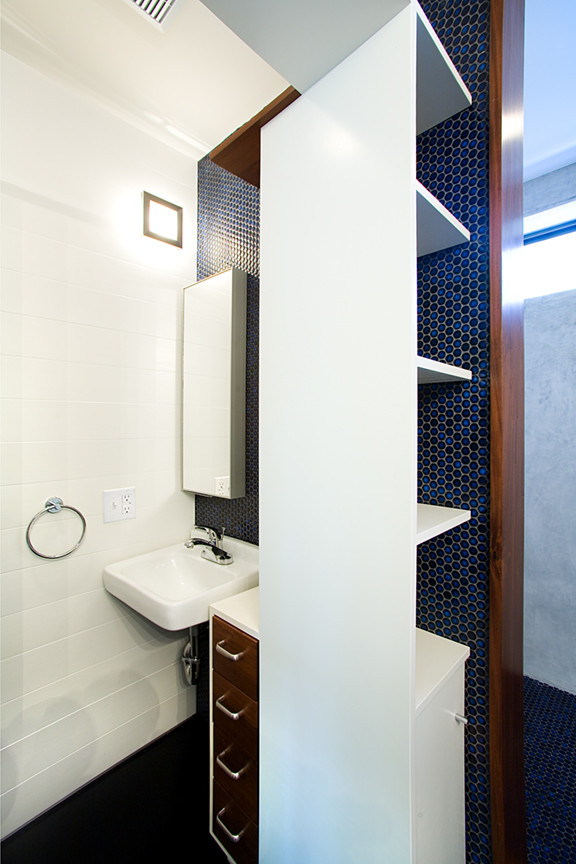 Foto på ett mellanstort funkis badrum med dusch, med vita skåp, blå kakel, vita väggar, ett väggmonterat handfat, öppna hyllor och klinkergolv i keramik