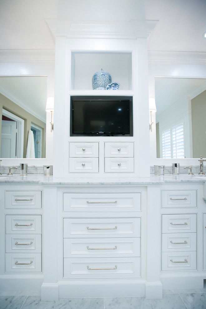 Modelo de cuarto de baño principal clásico grande con armarios con rebordes decorativos, puertas de armario blancas, encimera de mármol, bañera exenta, baldosas y/o azulejos blancos, paredes beige y suelo de mármol
