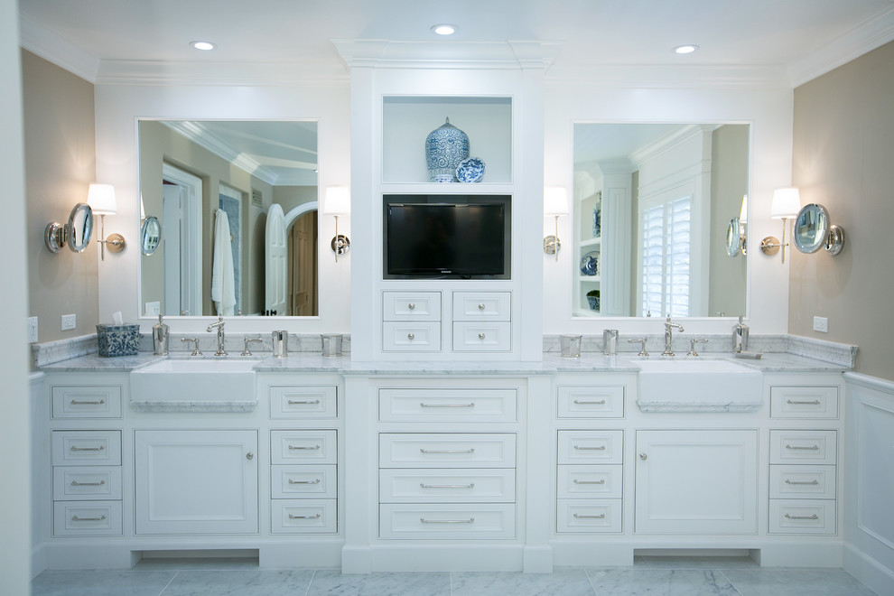 Idée de décoration pour une grande salle de bain principale tradition avec un placard à porte affleurante, des portes de placard blanches, un plan de toilette en marbre, une baignoire indépendante, un carrelage blanc, un mur beige et un sol en marbre.