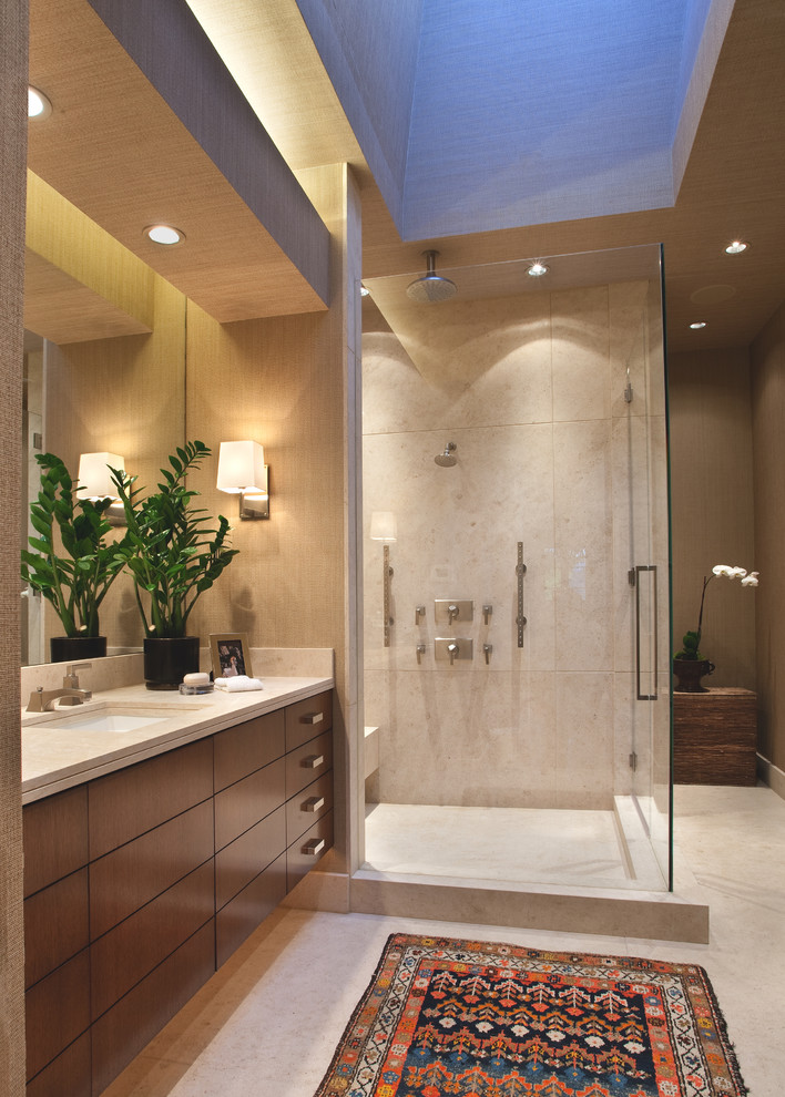 Design ideas for a large contemporary ensuite bathroom in Orange County with flat-panel cabinets, dark wood cabinets, a corner shower, beige tiles, stone tiles, beige walls, limestone flooring, a submerged sink, limestone worktops, beige floors and a hinged door.