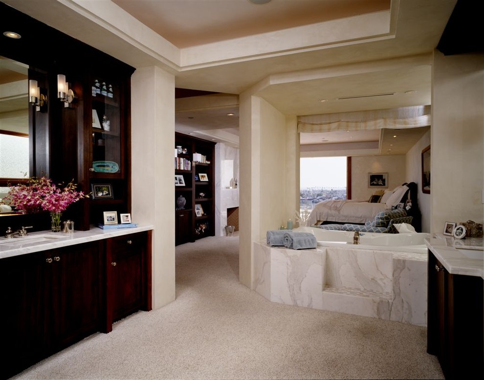 Klassisk inredning av ett badrum, med ett undermonterad handfat, skåp i mörkt trä och ett platsbyggt badkar