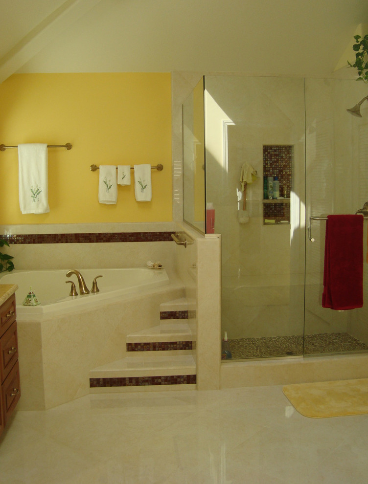 На фото: большая главная ванная комната в стиле неоклассика (современная классика) с настольной раковиной, фасадами с выступающей филенкой, фасадами цвета дерева среднего тона, столешницей из гранита, угловой ванной, угловым душем, раздельным унитазом, бежевой плиткой, каменной плиткой, желтыми стенами и мраморным полом