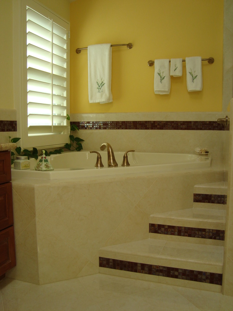 Immagine di una grande stanza da bagno padronale classica con lavabo a bacinella, ante con bugna sagomata, ante in legno scuro, top in granito, vasca ad angolo, doccia ad angolo, WC a due pezzi, piastrelle beige, piastrelle in pietra, pareti gialle e pavimento in marmo