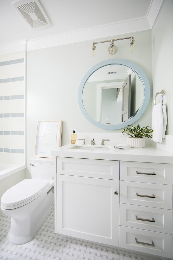 Maritim inredning av ett mellanstort badrum med dusch, med skåp i shakerstil, vita skåp, ett badkar i en alkov, en dusch/badkar-kombination, en toalettstol med hel cisternkåpa, blå kakel, vit kakel, cementkakel, gröna väggar, klinkergolv i porslin, ett undermonterad handfat, bänkskiva i akrylsten, vitt golv och med dusch som är öppen