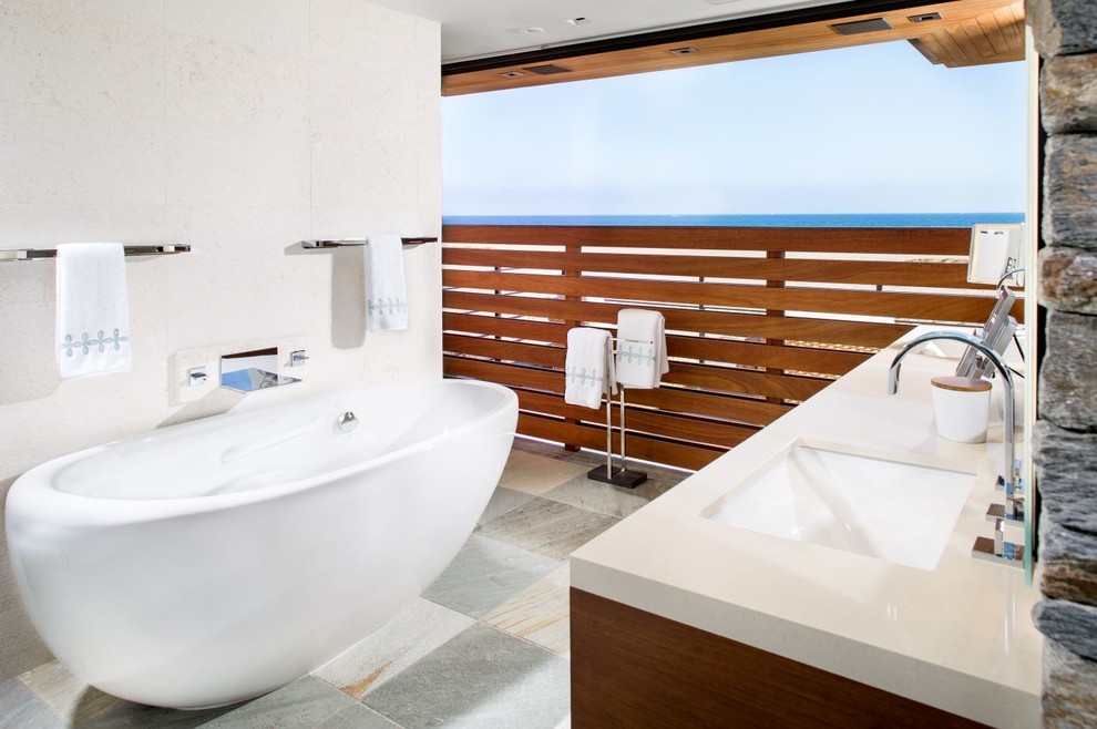Modelo de cuarto de baño principal contemporáneo de tamaño medio con puertas de armario de madera oscura, bañera exenta, lavabo bajoencimera, paredes blancas, suelo de pizarra y suelo gris