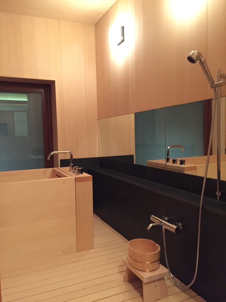 Idéer för mellanstora orientaliska en-suite badrum, med släta luckor, skåp i mellenmörkt trä, ett japanskt badkar, en dusch/badkar-kombination, en vägghängd toalettstol, svart kakel, stenhäll, vita väggar, mellanmörkt trägolv, ett undermonterad handfat och träbänkskiva