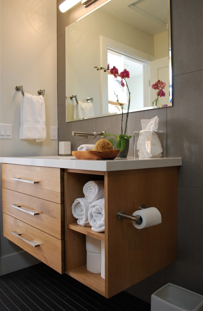 Medium sized midcentury shower room bathroom in Orange County with flat-panel cabinets, light wood cabinets, a walk-in shower, a one-piece toilet, grey tiles, porcelain tiles, white walls, ceramic flooring, a submerged sink, engineered stone worktops, black floors, an open shower and white worktops.