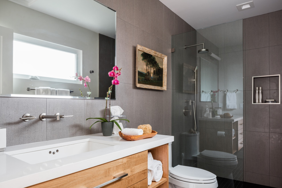 Foto di una stanza da bagno con doccia minimal di medie dimensioni con ante lisce, ante in legno scuro, doccia alcova, piastrelle grigie, lavabo sottopiano e top bianco
