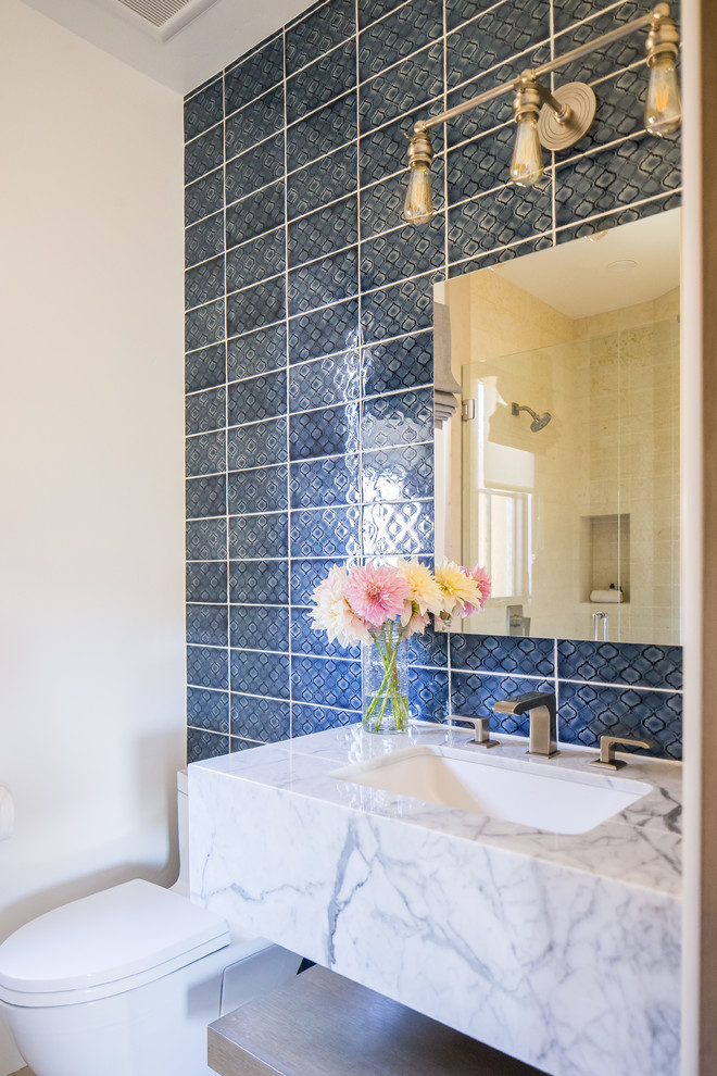 Foto på ett stort medelhavsstil vit badrum med dusch, med öppna hyllor, en dusch i en alkov, blå kakel, vita väggar, ett undermonterad handfat och dusch med gångjärnsdörr