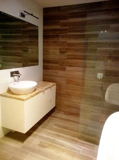 This is an example of a medium sized modern ensuite bathroom in Melbourne with a vessel sink, white cabinets, marble worktops, a freestanding bath, a built-in shower, a one-piece toilet, white tiles, porcelain tiles, white walls and light hardwood flooring.