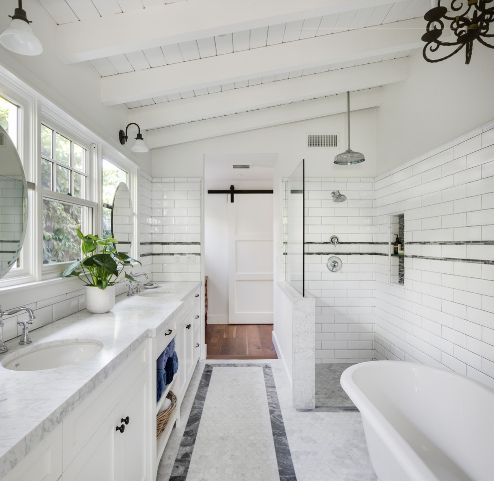 На фото: главная ванная комната в стиле кантри с фасадами в стиле шейкер, белыми фасадами, отдельно стоящей ванной, угловым душем, плиткой кабанчик, белыми стенами, врезной раковиной, мраморной столешницей и открытым душем