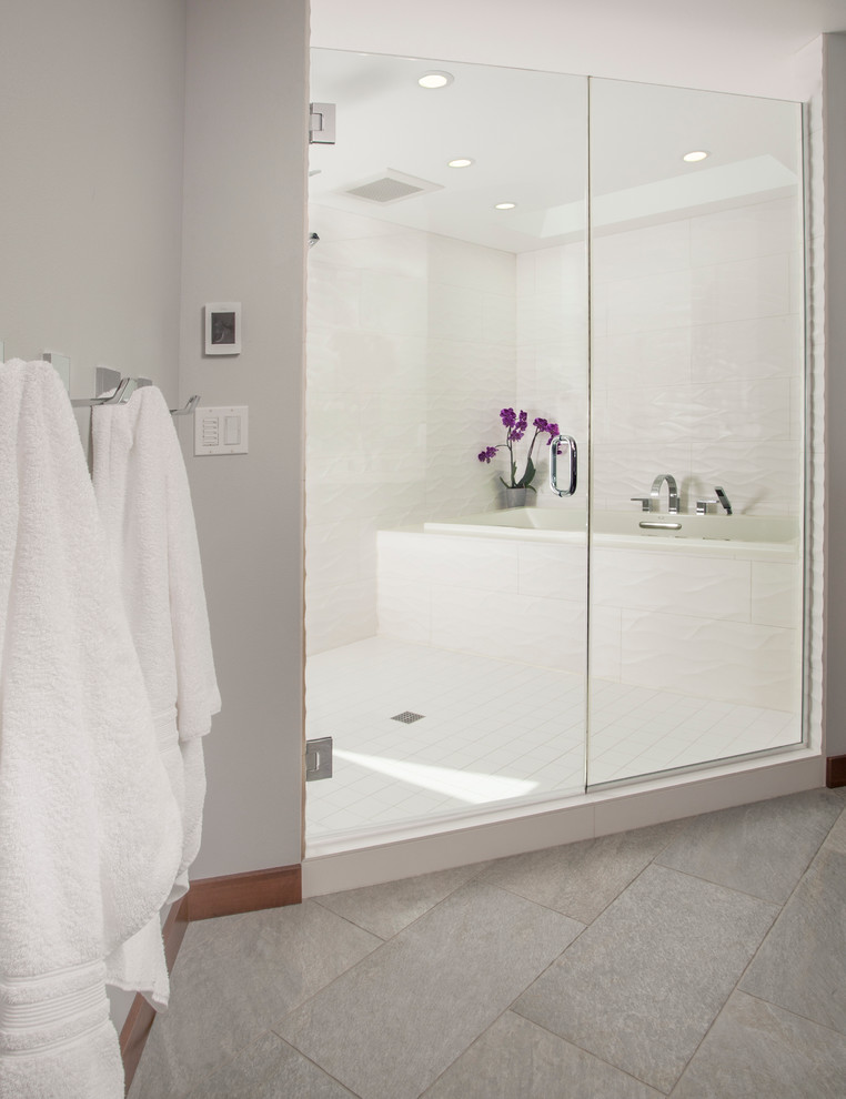 This is an example of a medium sized contemporary ensuite bathroom in Seattle with flat-panel cabinets, dark wood cabinets, a built-in bath, a shower/bath combination, a two-piece toilet, white tiles, porcelain tiles, grey walls, porcelain flooring, a submerged sink and engineered stone worktops.