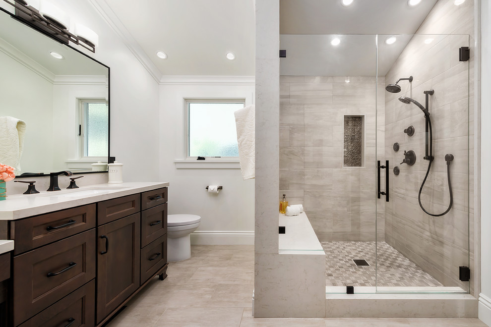 Inredning av ett klassiskt mellanstort en-suite badrum, med bruna skåp, en dusch i en alkov, en toalettstol med hel cisternkåpa, klinkergolv i porslin, bänkskiva i kvarts, beiget golv, dusch med gångjärnsdörr, skåp i shakerstil, vita väggar och ett undermonterad handfat