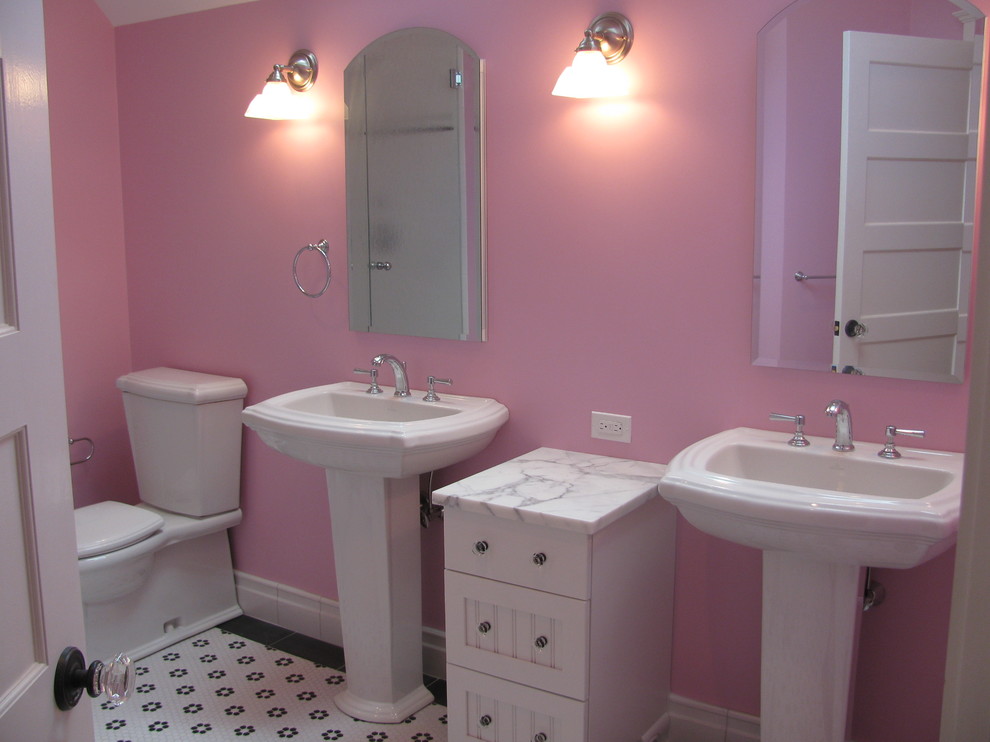 Diseño de cuarto de baño infantil tradicional de tamaño medio con armarios con paneles empotrados, puertas de armario blancas, sanitario de dos piezas, paredes rosas, suelo con mosaicos de baldosas, lavabo con pedestal y suelo multicolor
