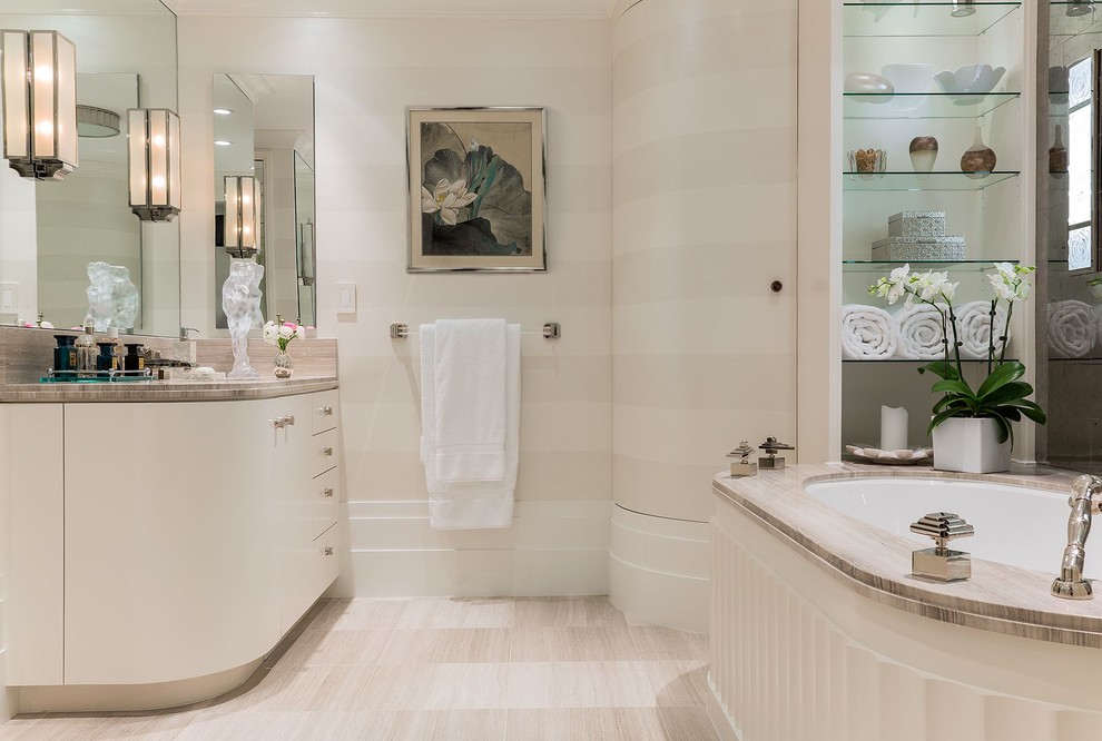 Cette image montre une salle de bain traditionnelle avec un lavabo encastré, un placard à porte plane, des portes de placard beiges, une baignoire encastrée et un mur beige.