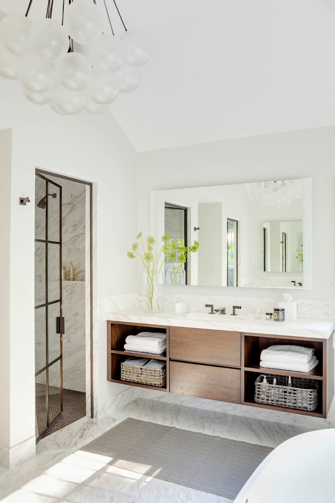 Example of a transitional white tile white floor alcove shower design in Boston with flat-panel cabinets, medium tone wood cabinets, gray walls, an undermount sink, a hinged shower door and white countertops