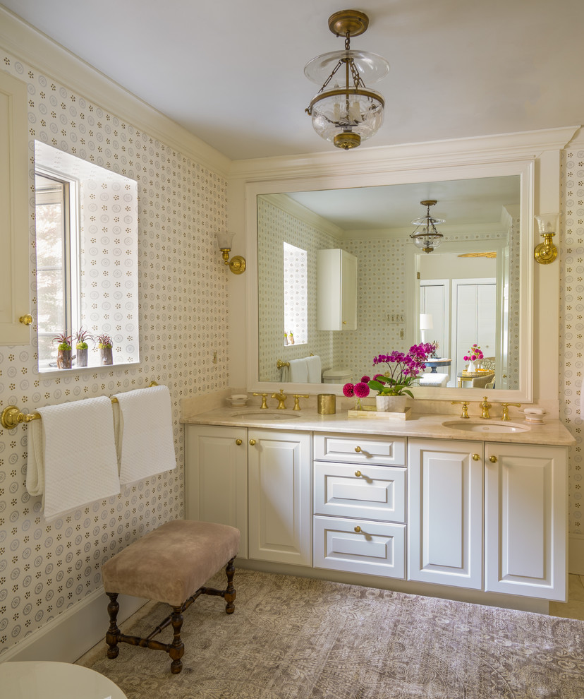 Cette image montre une salle d'eau traditionnelle avec un placard avec porte à panneau surélevé, des portes de placard blanches, un mur beige, un sol en marbre, un lavabo encastré, un plan de toilette en marbre et un sol beige.