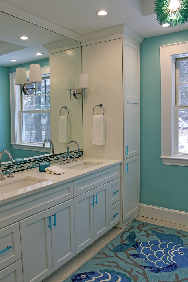Medium sized traditional family bathroom in Boston with recessed-panel cabinets, white cabinets, an alcove bath, a shower/bath combination, a two-piece toilet, white tiles, glass tiles, blue walls, porcelain flooring, a submerged sink, engineered stone worktops, grey floors, a sliding door and white worktops.