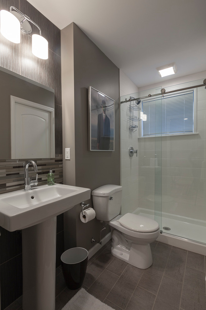 This is an example of a small contemporary bathroom in New York with an alcove shower, a two-piece toilet, white tiles, ceramic tiles, grey walls, porcelain flooring, a pedestal sink, grey floors and a sliding door.