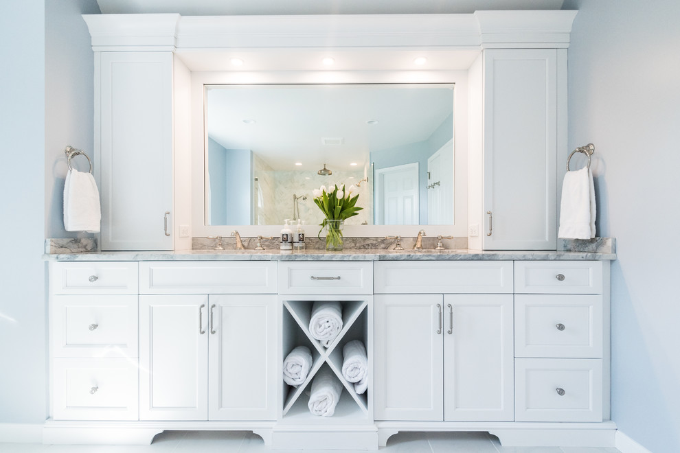 Photo of a medium sized traditional ensuite bathroom in Philadelphia with white cabinets, a freestanding bath, porcelain tiles, quartz worktops, flat-panel cabinets, a walk-in shower, a one-piece toilet, white tiles, blue walls, porcelain flooring, a submerged sink, white floors and a hinged door.