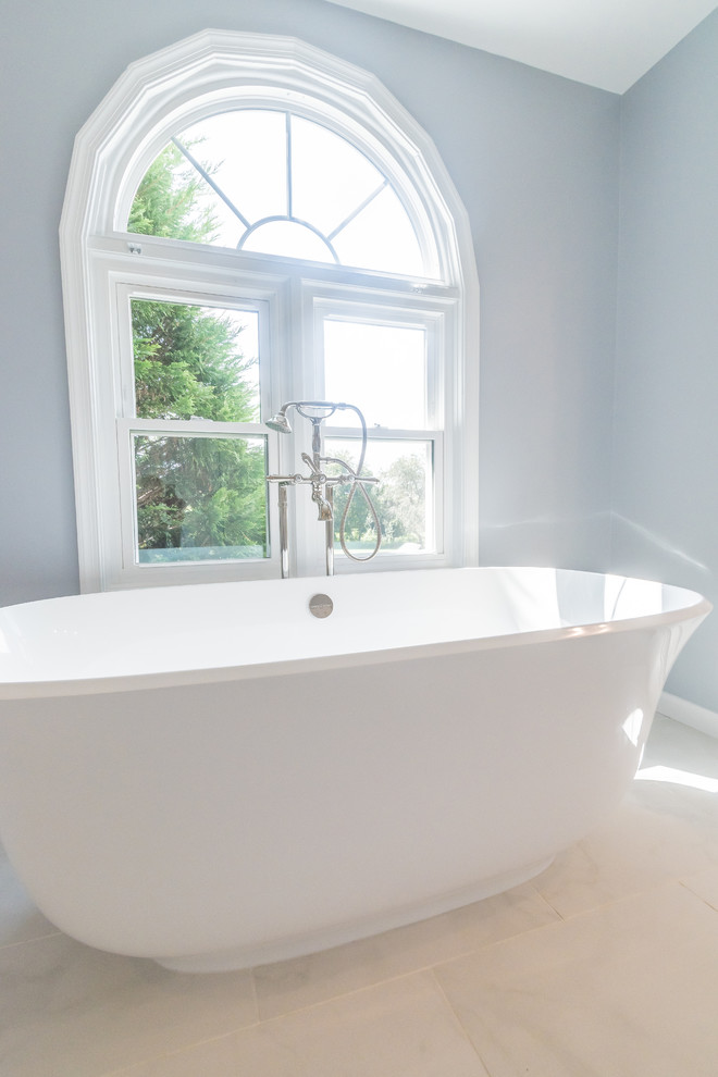 Klassisk inredning av ett mellanstort en-suite badrum, med vita skåp, ett fristående badkar, en bidé, porslinskakel och bänkskiva i kvartsit