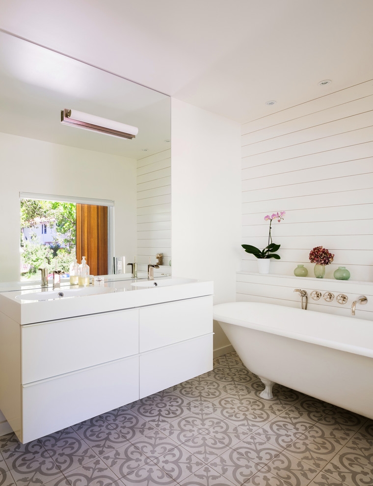 Modelo de cuarto de baño contemporáneo con armarios con paneles lisos, puertas de armario blancas, bañera con patas, paredes blancas, suelo de azulejos de cemento y lavabo tipo consola